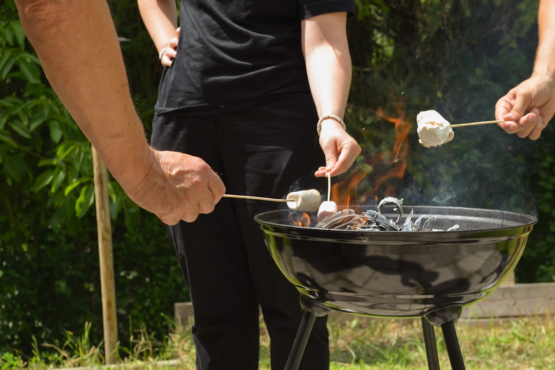 Person grilling various foods on a barbecue at night.